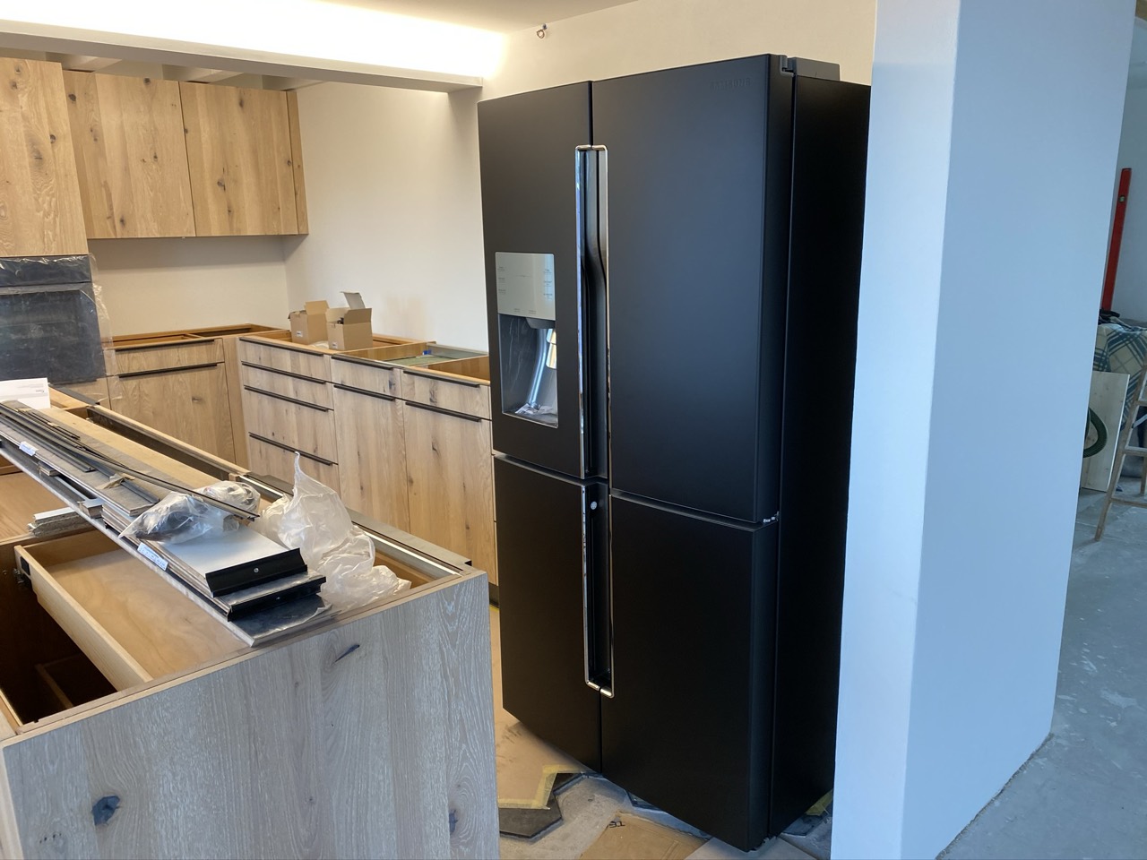 Küche mit folierten Fronten und schwarzem Kühlschrank